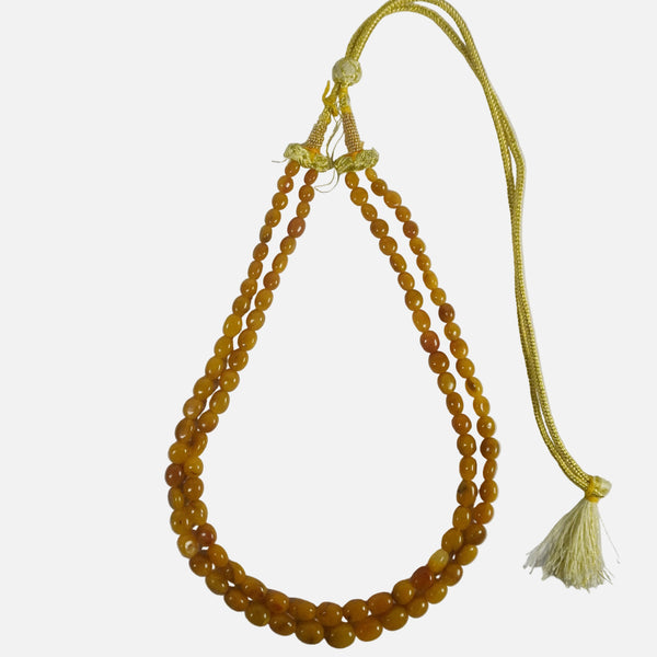 String of amber-colored beads with a yellow tassel on a white background